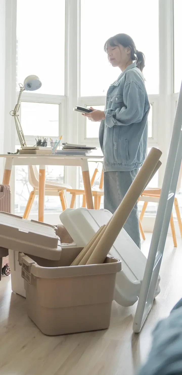 Organiserad flytt med plastlådor och resväskor i ett ljust rum – trygg hantering med professionell flyttfirma Täby.